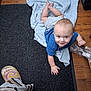 Christopher is registered to the contest to win money with this photo: baby, child, crawling, blue_shirt, gray_shorts, blanket, carpet, floor, plastic_bag, slipper, wooden_floor, indoor, person, smile, hand, footwear, clothing, head, cute, playful