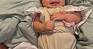 Keely is registered to the contest to win money with this photo: baby, infant, smiling, bow_headband, headwear, onesie, knee_high_socks, bed, blanket, pillow, happy, cute, child, face, skin, person, indoor, text_overlay, chat_message, social_media