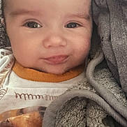 Dawson is registered to the contest to win money with this photo: baby, face, blanket, clothing, child, portrait, infant, expression, cozy, warm, cute, person, eyes, head, smile, soft, texture, indoors, young, wrapped