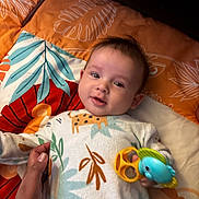 Aaron a rejoint le concours — aidez-le/la à gagner de superbes lots ! baby, child, toy, onesie, hand, blanket, pattern, animal_print, smile, face, infant, colorful, cute, lying_down, comfort, young_child, indoor, cozy, holding, playful