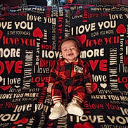 Chance joined the competition — help win amazing prizes! baby, smiling, cuddle_bear, red_black_checkered, onesie, blanket, love_you, heart, couch, happy, child, infant, sitting, cozy, indoor, text_pattern, footwear, cute, portrait, warm