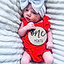 baby, infant, one_month, red_clothing, white_bow, headband, blanket, soft_texture, cute, newborn, portrait, lying_down, skin, hand, face, expression, milestone, wooden_sign, baby_girl, closeup