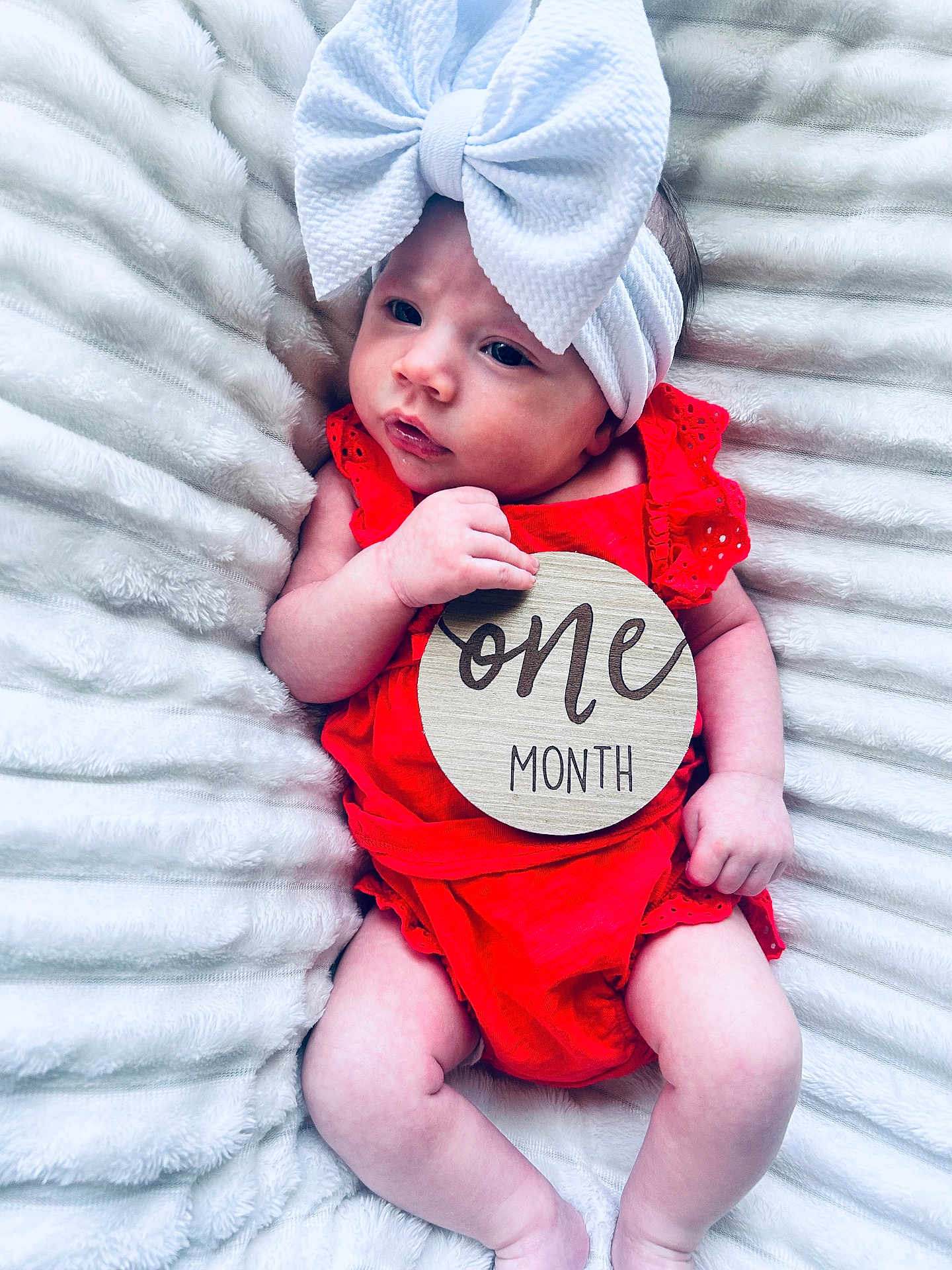 Adley joined the competition — help win amazing prizes! baby, infant, one_month, red_clothing, white_bow, headband, blanket, soft_texture, cute, newborn, portrait, lying_down, skin, hand, face, expression, milestone, wooden_sign, baby_girl, closeup