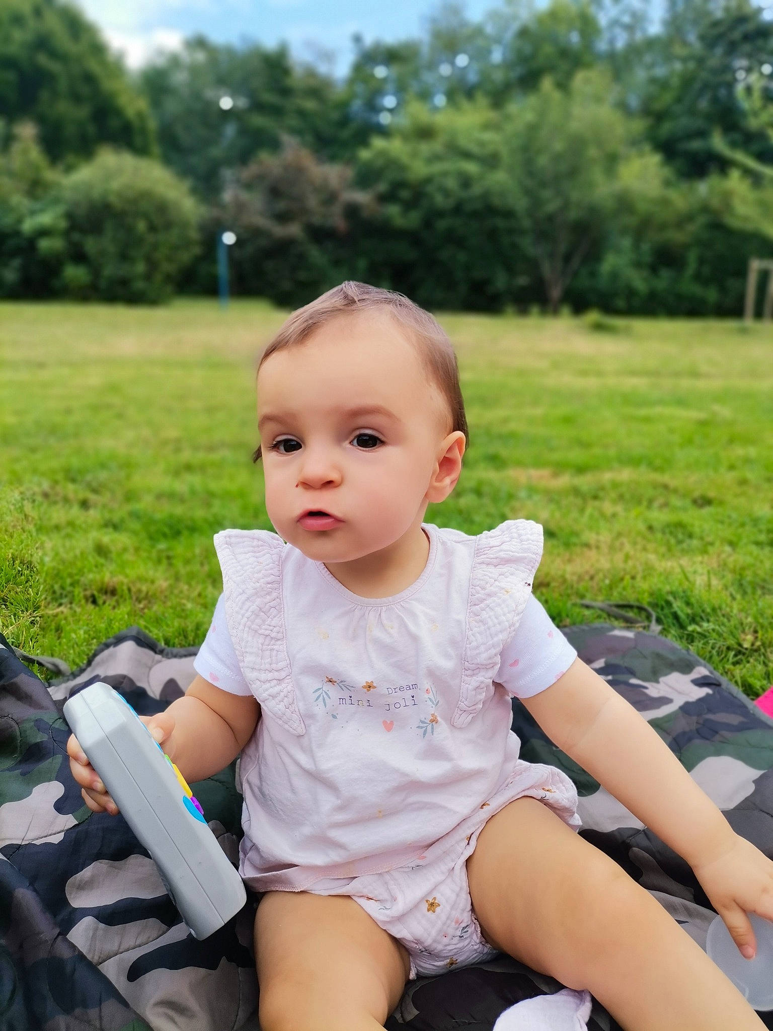 Maloe a rejoint le concours — aidez-le/la à gagner de superbes lots ! baby, baby_toddler_clothing, fun, grass, green, happy, lap, leisure, people_in_nature, person, pink, plant, recreation, shorts, sitting, skin, sky, sleeve, thigh, toddler