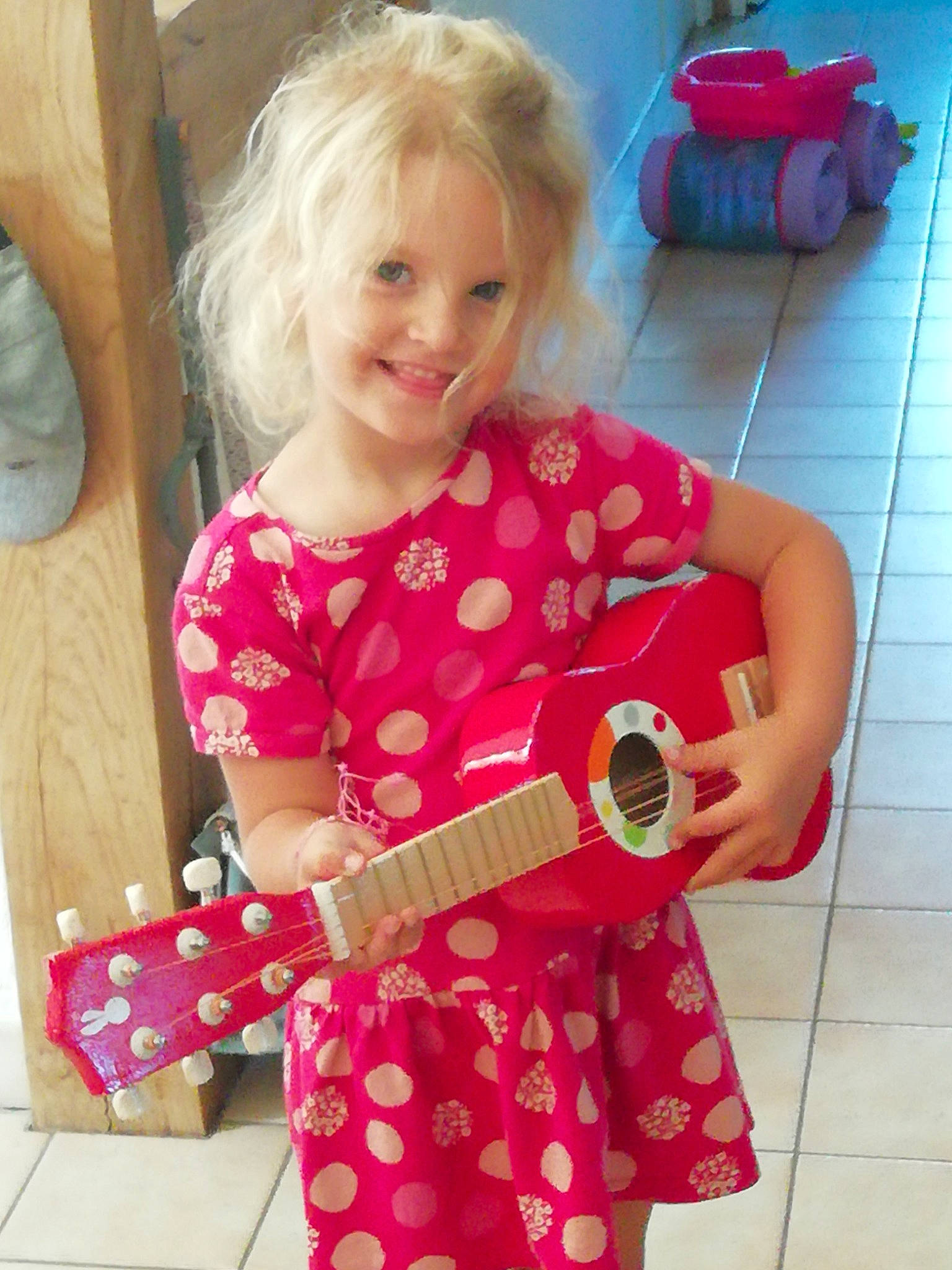 Lia participe au concours pour gagner de l'argent avec cette photo : baby_toddler_clothing, child, dress, fun, guitar, guitar_accessory, happy, joy, magenta, musical_instrument, pattern, person, pink, plucked_string_instruments, sitting, sleeve, smile, standing, string_instrument, string_instrument_accessory