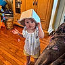 toddler, child, indoor, wooden_floor, cabinet, toy, plastic_container, shirt, shorts, barefoot, blanket, butterfly_pattern, curious, standing, home, furniture, playful, person, face, expression