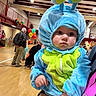 Vivian joined the competition — help win amazing prizes! baby, costume, blue, green, indoor, event, balloons, child, person, face, cute, clothing, headgear, holding, people, gymnasium, floor, celebration, fun, portrait