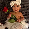baby, child, tutu, white_bow, rose, flower, smile, tongue_out, bare_chest, gold_necklace, earrings, soft_blanket, cute, portrait, infant, happy, lying_down, playful, adorable, accessories