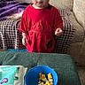 Merlin joined the competition — help win amazing prizes! blanket, blue_bowl, carpet, child, couch, curious, expression, food, fruit, home, indoor, looking_up, person, red_shirt, snack, standing, table, toddler, wipes, young_child