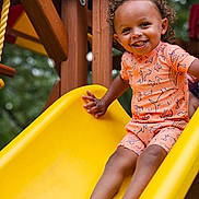 Maverick joined the competition — help win amazing prizes! toddler, child, smiling, slide, playground, yellow_slide, curly_hair, outdoor, wooden_structure, clothing, happy, fun, summer, play, barefoot, person, nature, daylight, casual_wear, recreation