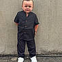Vincy a rejoint le concours — aidez-le/la à gagner de superbes lots ! child, boy, standing, black_clothing, white_shoes, concrete_wall, outdoor, pavement, casual, portrait, young, serious_expression, hands_behind_back, short_hair, full_body, fashion, urban, street, sidewalk, daylight