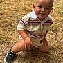 child, toddler, smiling, kneeling, grass, outdoor, striped_shirt, shorts, black_sneakers, gold_chain, happy, person, casual_clothing, summer, event, people, background, blurred, fun, daylight