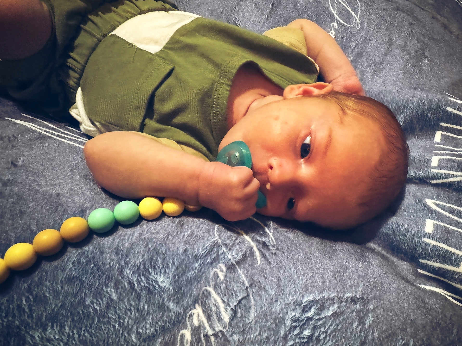 Walker joined the competition — help win amazing prizes! baby, pacifier, blanket, beads, infant, lying_down, clothing, hand, face, head, skin, young_child, resting, indoors, comfort, sleepwear, closeup, portrait, cute, child