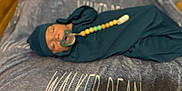 Walker joined the competition — help win amazing prizes! baby, pacifier, swaddle, hat, sleeping, blanket, beads, wooden_floor, infant, clothing, face, person, indoors, resting, cute, newborn, soft_texture, peaceful, lying_down, comfort