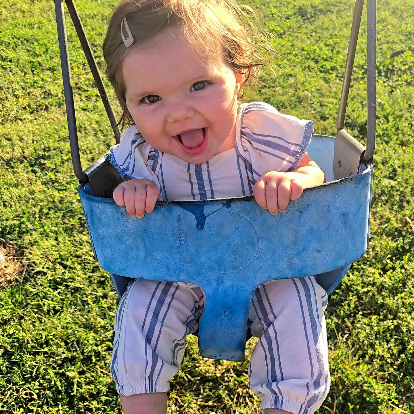 Rylee joined the competition — help win amazing prizes! baby, blue_swing, child, clothing, daylight, fun, grass, hair_clip, happy, joy, nature, outdoor, person, play, playground, seat, smiling, sunlight, swing, toddler
