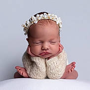 Eloise is registered to the contest to win money with this photo: newborn, baby, sleeping, flower_crown, knitted_sweater, hands_under_chin, peaceful, portrait, cute, infant, soft_background, skin, headwear, child, resting, cozy, closeup, baby_feet, adorable, expression