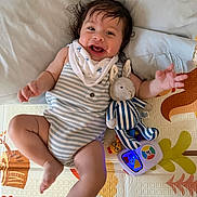 Iker is registered to the contest to win money with this photo: baby, blanket, child, clothing, cute, face, foot, hand, happy, indoor, infant, joyful, lying_down, person, play_mat, plush_bunny, smiling, striped_outfit, toy, young_child