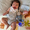 baby, blanket, child, clothing, cute, face, foot, hand, happy, indoor, infant, joyful, lying_down, person, play_mat, plush_bunny, smiling, striped_outfit, toy, young_child