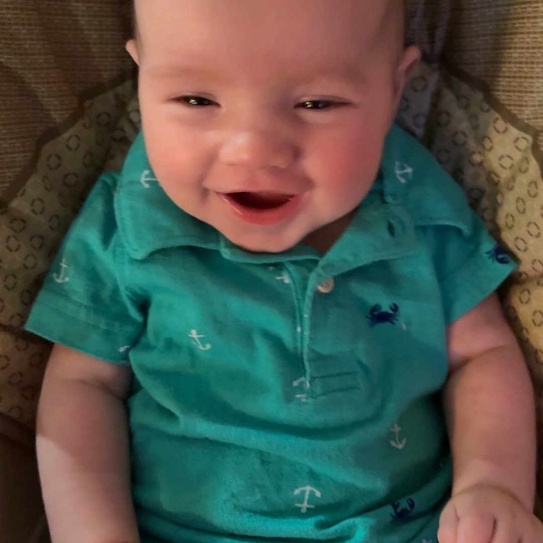 Haydn is registered to the contest to win money with this photo: anchors, baby, casual, child, clothing, comfort, crab, cushioned_seat, cute, face, hands, happy, indoor, infant, person, portrait, sitting, smiling, teal_shirt, young