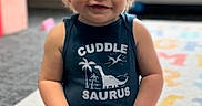 Gunner is registered to the contest to win money with this photo: toddler, child, baby, smiling, sitting, portrait, indoor, home, floor, rug, carpet, dinosaur, onesie, clothing, blond_hair, blue_eyes, window, daylight, smartphone_screenshot, lock_screen