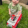 Gunner joined the competition — help win amazing prizes! toddler, child, baby, portrait, outdoor, grass, fire_truck, ride_on_toy, toy_vehicle, red, green_shirt, blond_hair, blue_eyes, smiling, sitting, standing, playtime, backyard, brick_wall, safe