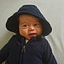 baby, baby_face, blue_clothing, casual_wear, child, clothing, cute, expression, face, hood, hoodie, indoors, infant, lying_down, person, portrait, smile, soft_surface, young_child, zipped_jacket
