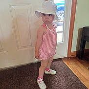 Nai'Ema is registered to the contest to win money with this photo: toddler, child, indoor, door, hat, romper, pink, white, socks, shoes, carpet, wood_floor, window, curious, standing, footwear, young_child, person, expression, casual