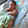 baby, infant, blanket, baby_seat, sitting, hand_in_mouth, curious, indoor, quilt, clothing, striped_socks, face, child, person, cute, comfort, soft, colorful, pattern, furniture