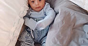 Ethan is registered to the contest to win money with this photo: baby, infant, pillow, blanket, bed, clothing, sneakers, person, indoor, cute, child, portrait, young, cozy, sleepwear, soft, rest, comfort, small, curious