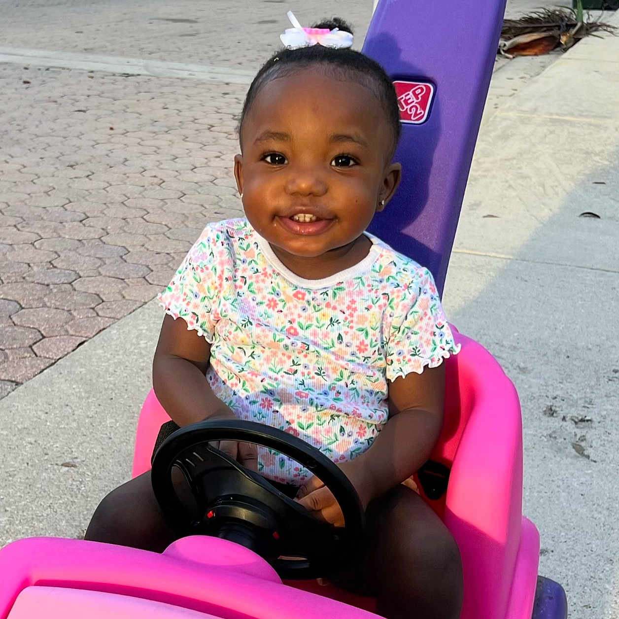 Ariella is registered to the contest to win money with this photo: child, clothing, face, female, girl, grass, happy, head, nature, outdoors, person, photography, playarea, portrait, purple, sitting, smile, t_shirt, transportation, vehicle