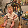 Riley joined the competition — help win amazing prizes! baby, infant, child, high_chair, smiling, happy, portrait, sitting, indoor, kitchen, home, grocery, snacks, cereal, food, chair, wooden_table, baby_clothing, bare_feet, family_photo