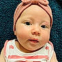 baby, infant, headband, bow, pink, striped_clothing, hands, face, eyes, skin, cheeks, lying_down, blanket, blue_background, closeup, portrait, cute, child, soft_texture, expression