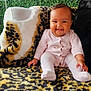 baby, child, smiling, pink_clothing, onesie, leopard_print, blanket, chair, plush, fur, greenery, plants, indoor, portrait, happy, sitting, face, cute, infant, cozy