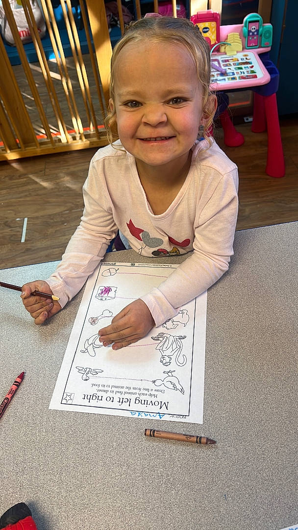 Amaya joined the competition — help win amazing prizes! baby, chair, child, finger, flooring, font, fun, handwriting, happy, joy, office_supplies, pen, person, sitting, smile, stationery, table, toddler, wood, writing