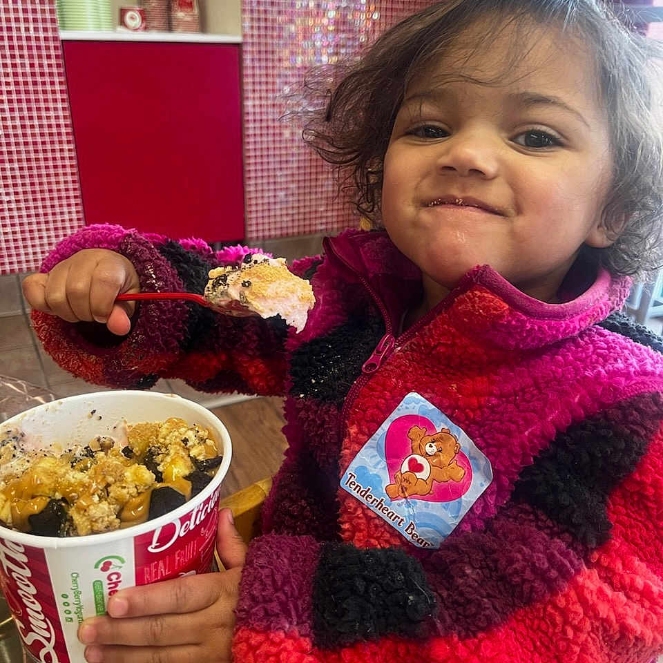 Sophia is registered to the contest to win money with this photo: baby, bodypart, clothing, coat, cutlery, face, finger, food, head, jacket, knitwear, lunch, meal, person, photography, popcorn, portrait, snack, spoon, sweater