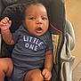 Kairo is registered to the contest to win money with this photo: baby, infant, child, onesie, clothing, seat, baby_seat, face, hand, leg, indoor, home, kitchen, expression, curious, sitting, cushion, person, young_child, cute