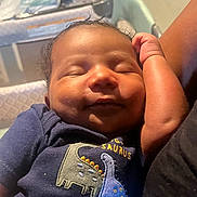 Kairo joined the competition — help win amazing prizes! baby, infant, sleeping, curly_hair, onesie, dinosaur, navy_blue, arm, person, closeup, face, peaceful, child, resting, indoors, soft_light, cute, newborn, smiling, skin