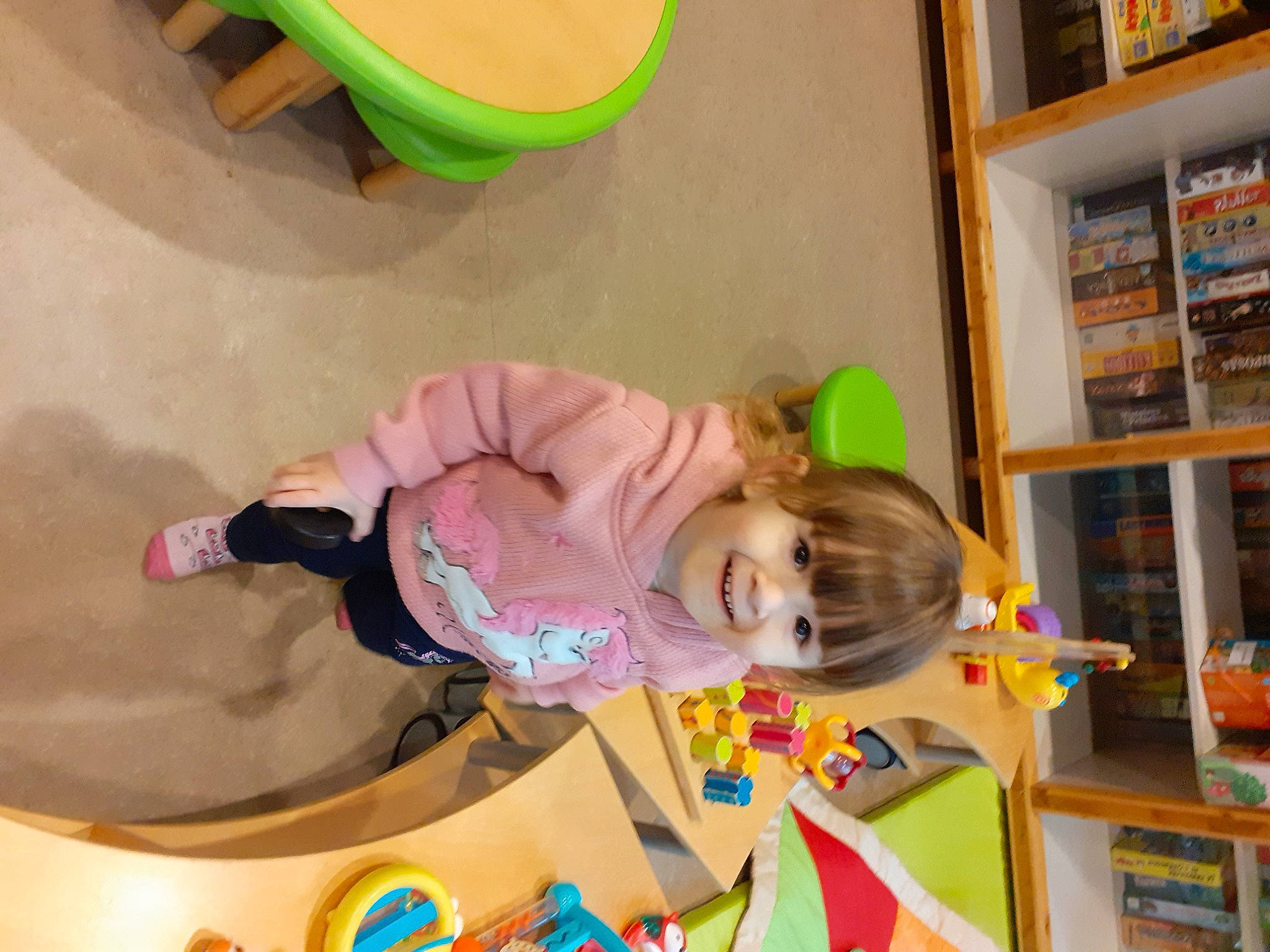 Yona a rejoint le concours — aidez-le/la à gagner de superbes lots ! baby, baby_toddler_clothing, baby_toys, bookcase, child, circle, flooring, fun, green, happy, joy, kindergarten, leisure, person, play, recreation, room, shelf, shelving, smile