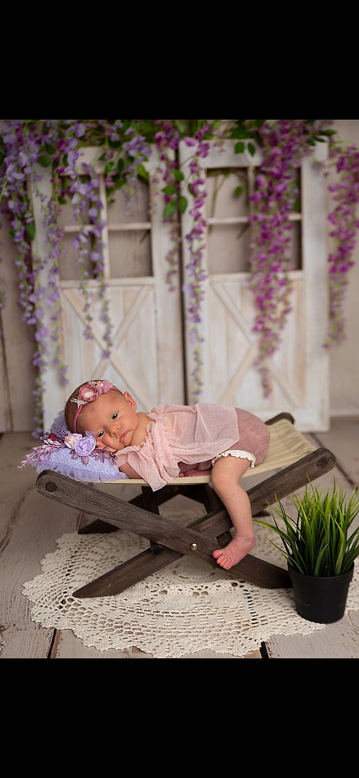 Lila a rejoint le concours — aidez-le/la à gagner de superbes lots ! baby, baby_toddler_clothing, chair, child, comfort, dress, flooring, flower_arranging, grass, hat, human_leg, leisure, magenta, person, pink, plant, purple, sandal, sitting, toddler