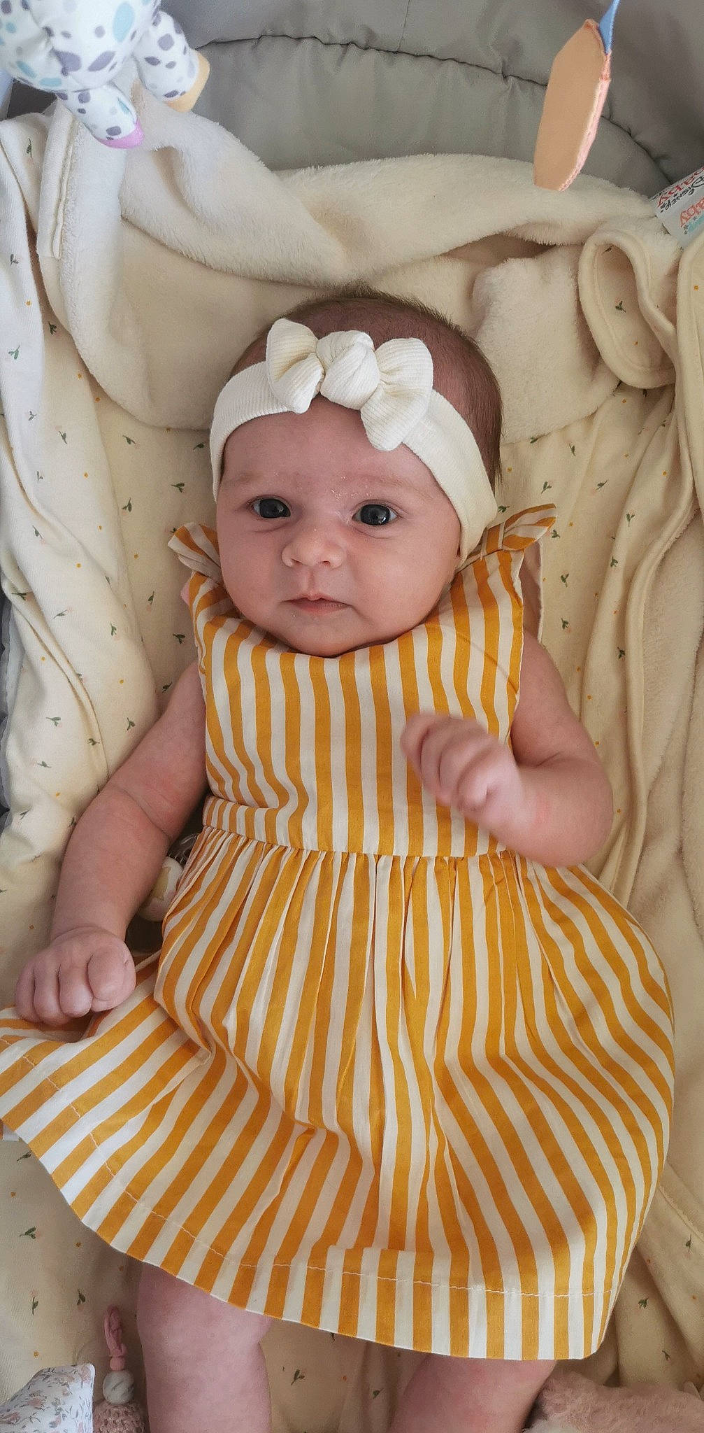 Lya participe au concours pour gagner de l'argent avec cette photo : baby, baby_products, baby_toddler_clothing, cap, cheek, child, comfort, day_dress, face, headwear, iris, linens, one_piece_garment, pattern, person, pink, sitting, skin, sleeve, textile