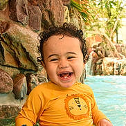 Kyan a rejoint le concours — aidez-le/la à gagner de superbes lots ! toddler, child, smiling, water, pool, yellow_shirt, curly_hair, happy, outdoor, rocks, greenery, sitting, splashing, sunlight, swimwear, cute, young_child, water_fun, portrait, playful
