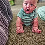 baby, child, surprised, blue_onesie, sitting, carpet, indoor, person, infant, cute, expression, home, floor, furniture, soft_light, blurry_background, skin, head, hands, feet