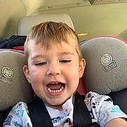 Walker is registered to the contest to win money with this photo: accessories, baby, belt, bodypart, clothing, cushion, face, happy, head, homedecor, laughing, mouth, person, photography, portrait, smile, t_shirt, teeth, transportation, vehicle