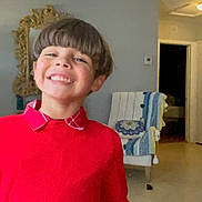 Jayden Noah Barrera joined the competition — help win amazing prizes! child, smile, red_sweater, indoor, haircut, face, happy, person, plaid_collar, mirror, chair, decor, home, furniture, portrait, young, boy, clothing, expression, casual