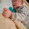 Kayson is registered to the contest to win money with this photo: baby, infant, sleeping, pacifier, portrait, close_up, face, hand, onesie, clothing, bed, blanket, pillow, indoors, cozy, resting, cuddled, peaceful, soft_lighting, nap