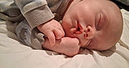 Kayson is registered to the contest to win money with this photo: newborn, baby, infant, sleeping, face, hands, fingers, closed_eyes, onesie, clothing, bed, bedding, blanket, indoors, portrait, close_up, peaceful, cozy, resting, photography