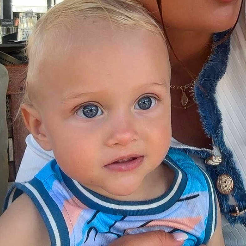 Vicenzo participe au concours pour gagner de l'argent avec cette photo : adult, baby, blond_hair, blue_eyes, casual_clothing, child, closeup, cute, expression, face, holding, human, indoor, looking_away, person, portrait, skin, sleeveless_shirt, toddler, young_child