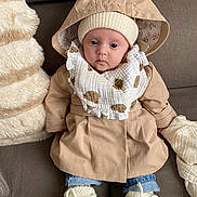Judith a rejoint le concours — aidez-le/la à gagner de superbes lots ! baby, infant, hooded_coat, knitted_hat, booties, scarf, couch, blanket, soft_texture, indoor, child, clothing, portrait, cute, warm, seated, cozy, face, person, expression