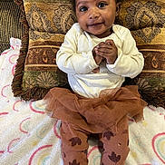 Zaniyah is registered to the contest to win money with this photo: baby, blanket, child, clothing, colorful, cozy, cute, fabric, face, happy, indoors, leggings, pattern, person, pillow, sitting, smiling, soft, tutu, young_child