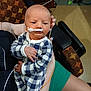 Maverick is registered to the contest to win money with this photo: newborn, baby, infant, checkered_clothing, medical_tube, taped_nose, adult_hand, indoor, chair, patterned_fabric, person, seated, legs, casual_clothing, hospital, medical_care, cute, small_hands, baby_garment, skin
